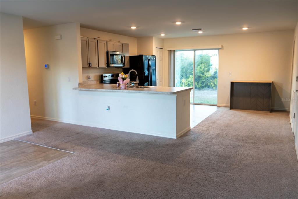 A kitchen with gray cabinets and a breakfast bar overlooks a carpeted living area — 22226 STATE AVENUE, PORT CHARLOTTE, FL