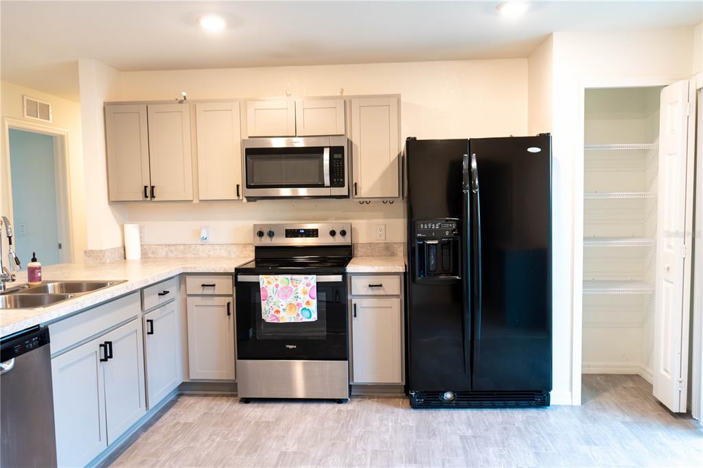 A kitchen features light gray cabinets, stainless steel appliances, a black refrigerator, and a pantry — 22226 STATE AVENUE, PORT CHARLOTTE, FL