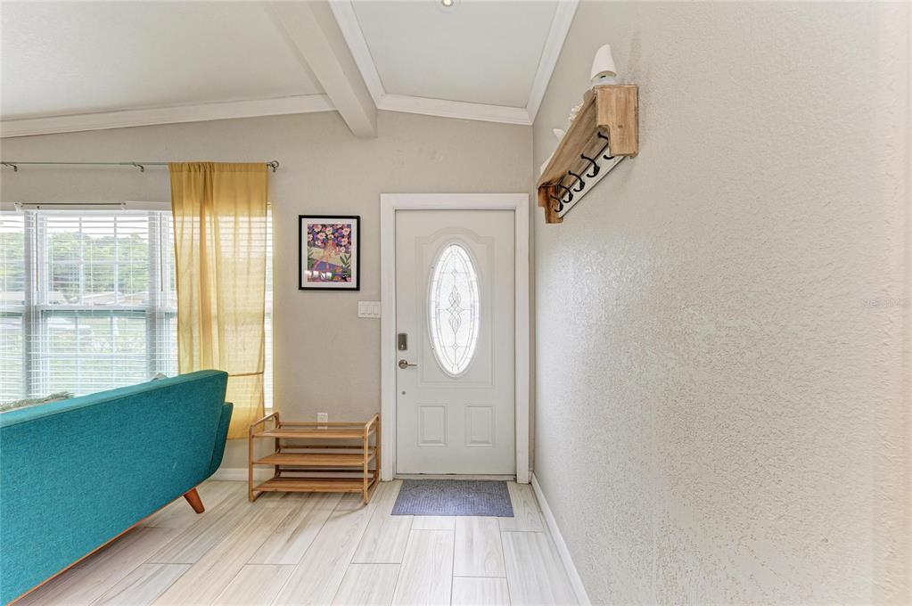 An entryway features a white front door, a wooden wall shelf, and light-colored tile flooring — 161 SUNTAN AVENUE, SARASOTA, FL
