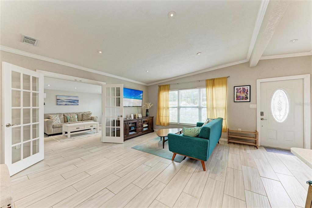 A living room features light tile flooring, a teal sofa, French doors, and a television console — 161 SUNTAN AVENUE, SARASOTA, FL