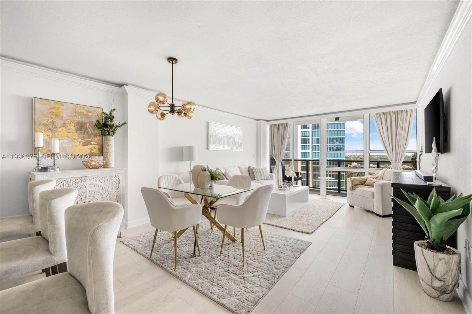A bright, open-concept living and dining area features white furniture, gold accents, and floor-to-ceiling windows — 600 NE 36th ST # 1414, Miami FL 33137, MIAMI, FL