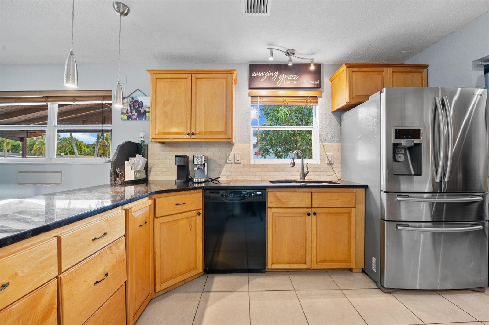 A kitchen features light wood cabinets, black countertops, stainless steel appliances, and a window — 5554 SW 6th Street, Margate FL 33068, MARGATE, FL