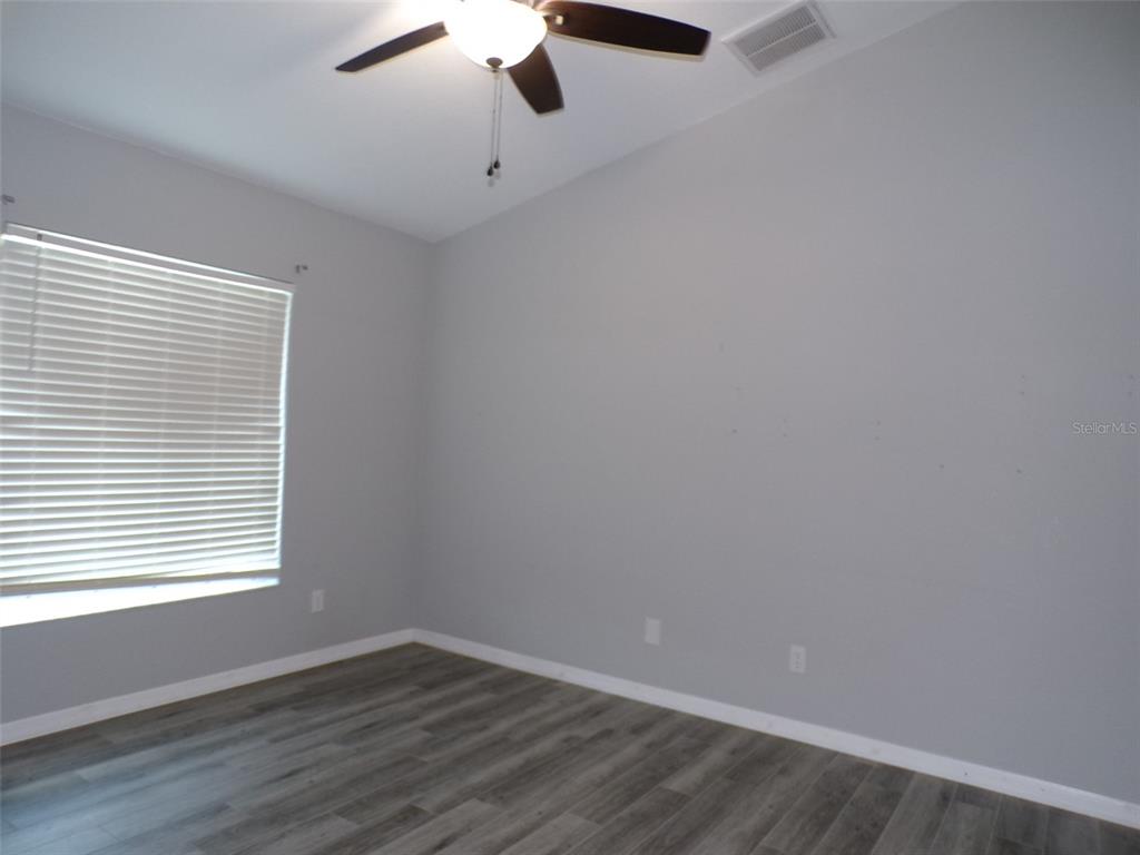 A bedroom with gray walls, wood-look flooring, a ceiling fan, and a window with blinds — 1077 ROTONDA CIRCLE, ROTONDA WEST, FL