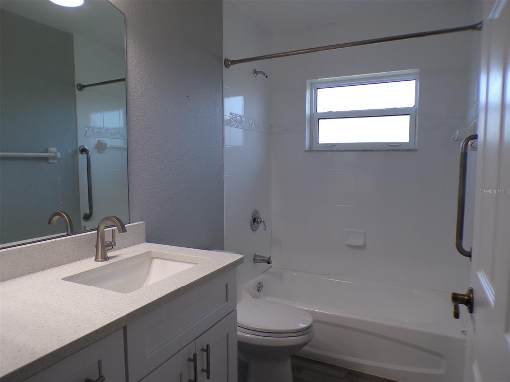 A bathroom features a white vanity with a stone countertop, a toilet, and a tub-shower — 1077 ROTONDA CIRCLE, ROTONDA WEST, FL