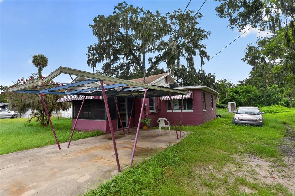 A single-story house with a metal carport and a red exterior sits on a grassy lot — 505 FULTON STREET, DAYTONA BEACH, FL