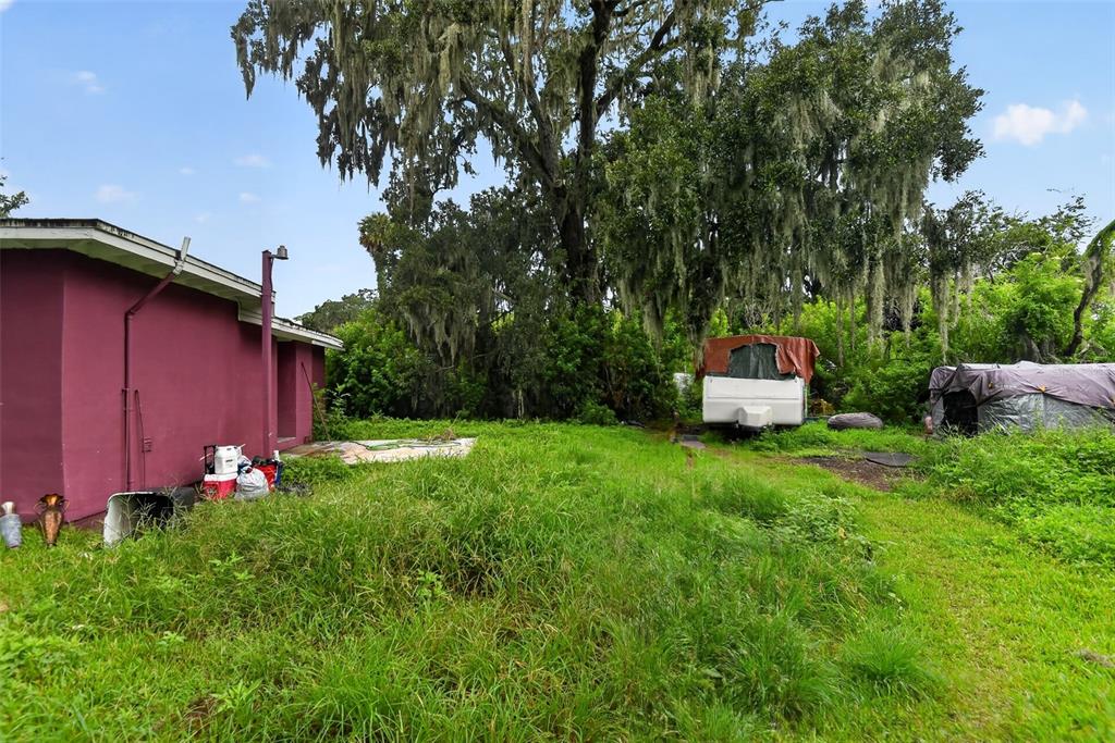 A purple exterior wall stands beside an overgrown yard with a camper and large trees — 505 FULTON STREET, DAYTONA BEACH, FL