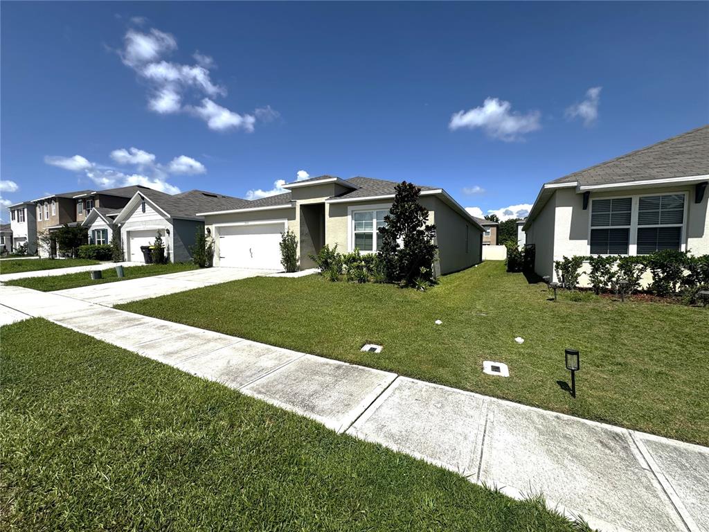 A suburban house with a white garage and a green lawn under a blue sky — 1622 REDDISH EGRET COURT, DAVENPORT, FL