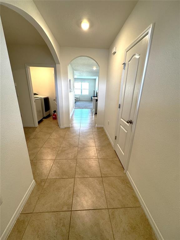 A tiled hallway features arched entryways, a laundry room to the left, and a closed door — 1622 REDDISH EGRET COURT, DAVENPORT, FL