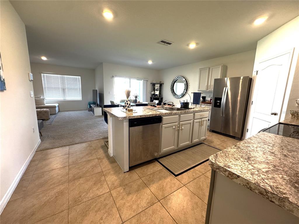 A kitchen with granite countertops and a central island overlooks an open-concept living area — 1622 REDDISH EGRET COURT, DAVENPORT, FL