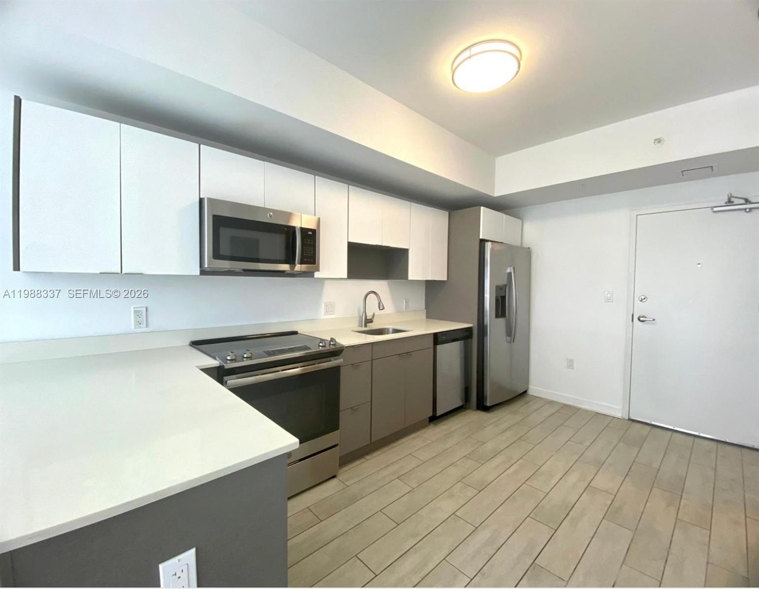 A modern kitchen features white upper cabinets, grey lower cabinets, stainless steel appliances, and tile flooring — 321 NE 26th St # 514, Miami FL 33137, MIAMI, FL