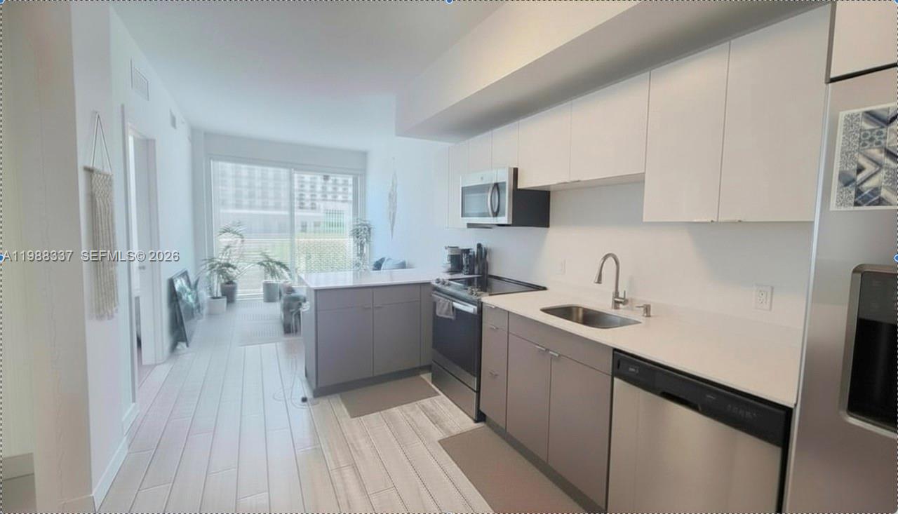 A modern kitchen features white upper cabinets, gray lower cabinets, stainless steel appliances, and countertops — 321 NE 26th St # 514, Miami FL 33137, MIAMI, FL
