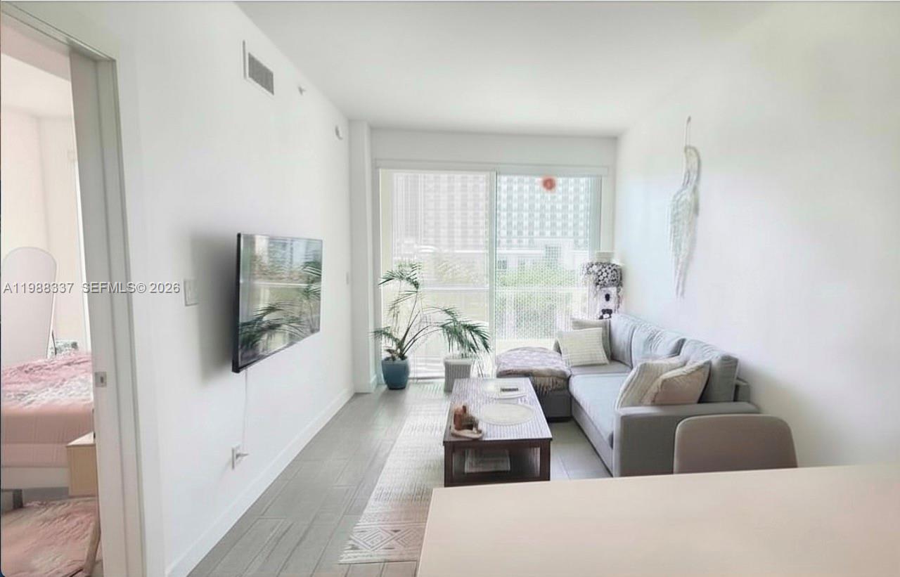 A living room features a grey sofa, wooden coffee table, and a balcony with city views — 321 NE 26th St # 514, Miami FL 33137, MIAMI, FL