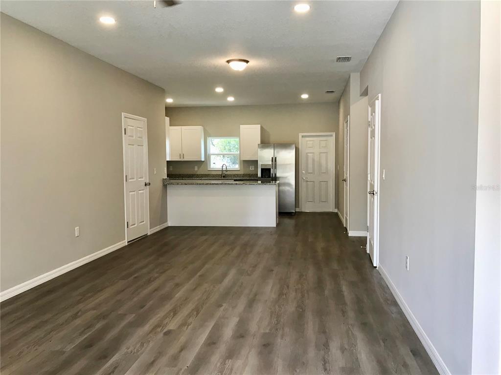 An open-concept kitchen with white cabinets and stainless steel appliances overlooks a living area — 5021 FINDERS COURT, TAMPA, FL