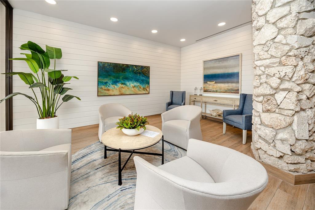 A modern waiting area features white shiplap walls, a stone pillar, and four armchairs — 7100 SUNSET WAY UNIT 810, ST PETE BEACH, FL