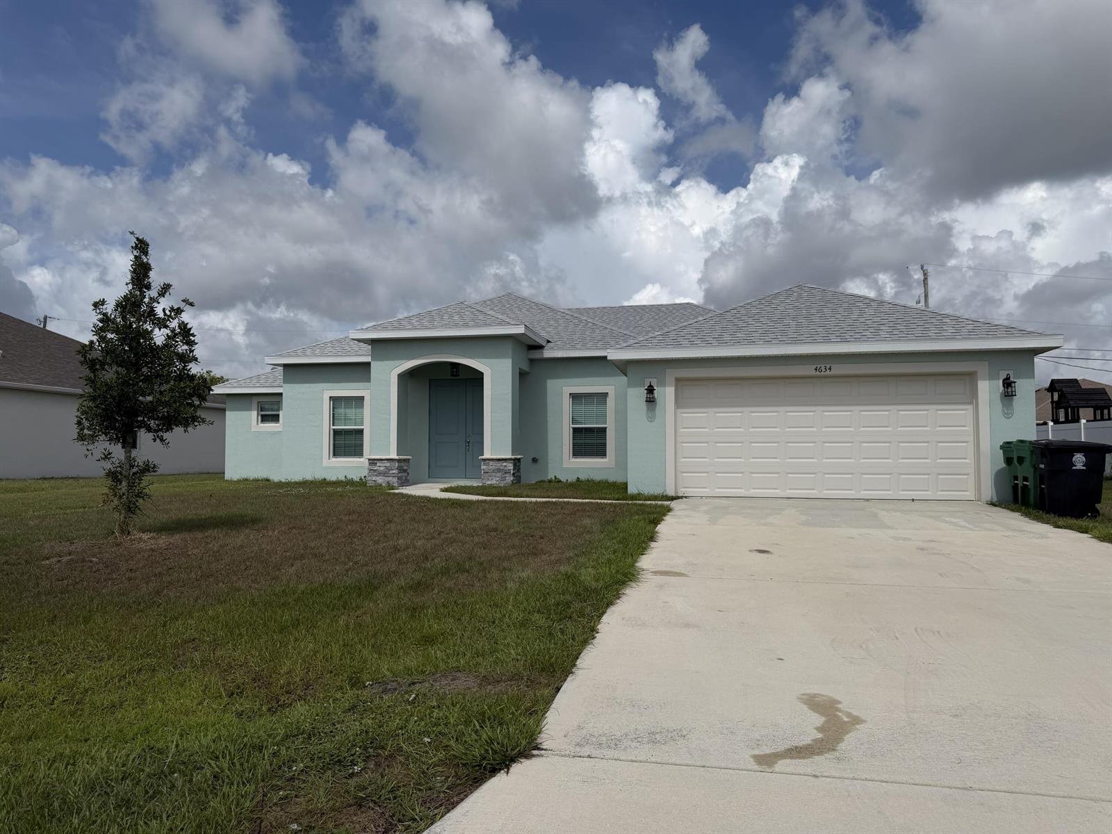 A light green single-story house with a two-car garage and a concrete driveway — 4634 SW Athena Drive, FL 34953, FL