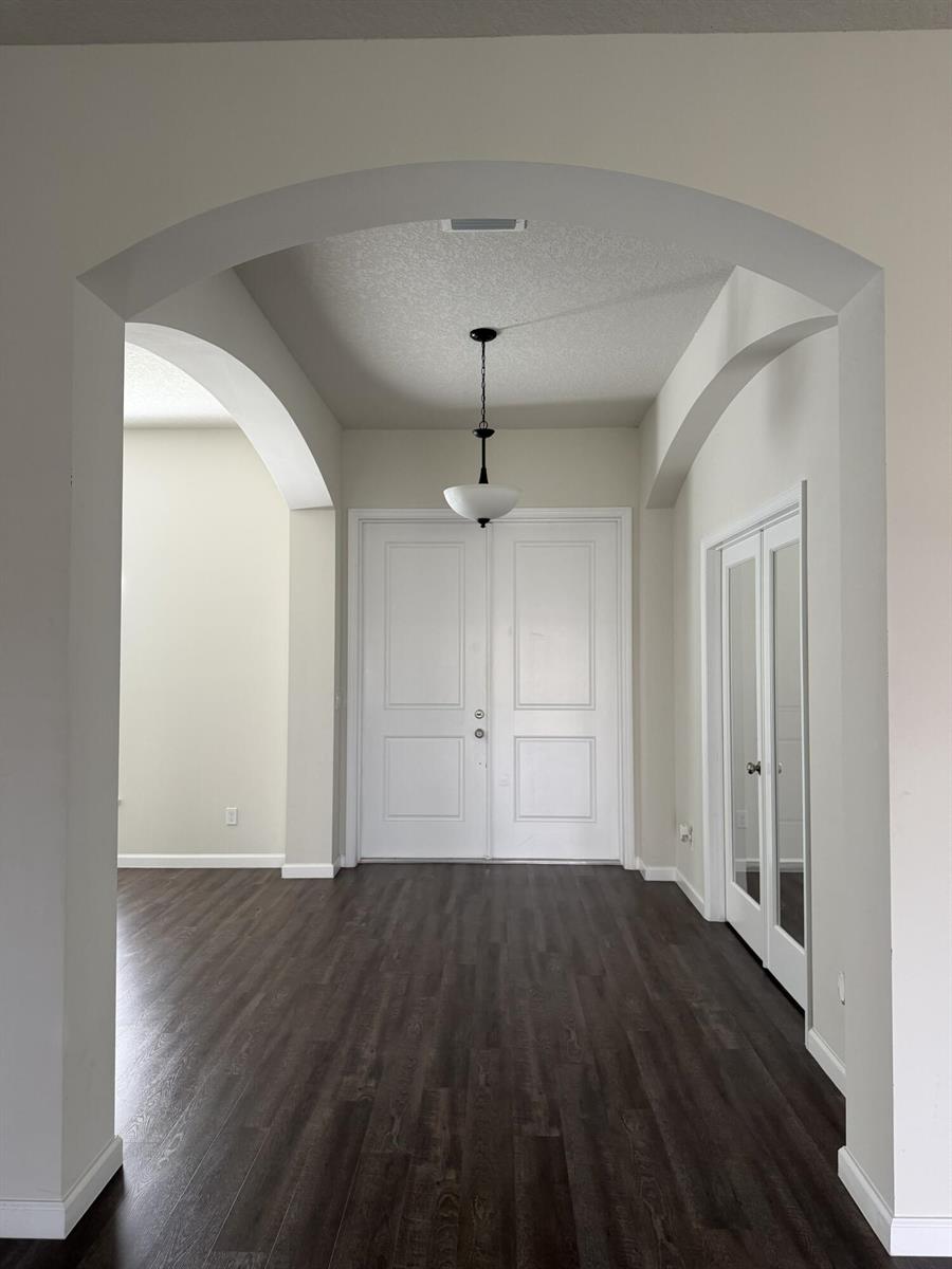An entryway features dark wood-look flooring, white double doors, and an arched ceiling transition — 4634 SW Athena Drive, FL 34953, FL