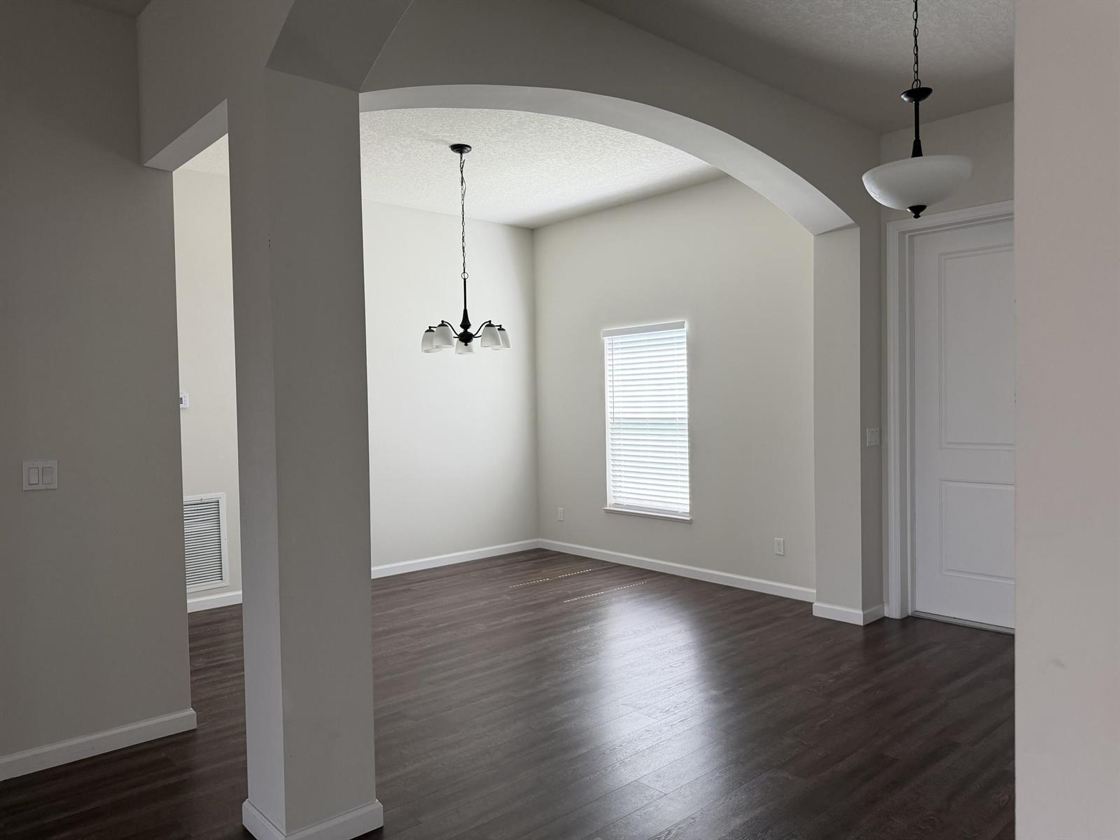 An empty dining room features dark wood flooring, a chandelier, and an arched entryway — 4634 SW Athena Drive, FL 34953, FL