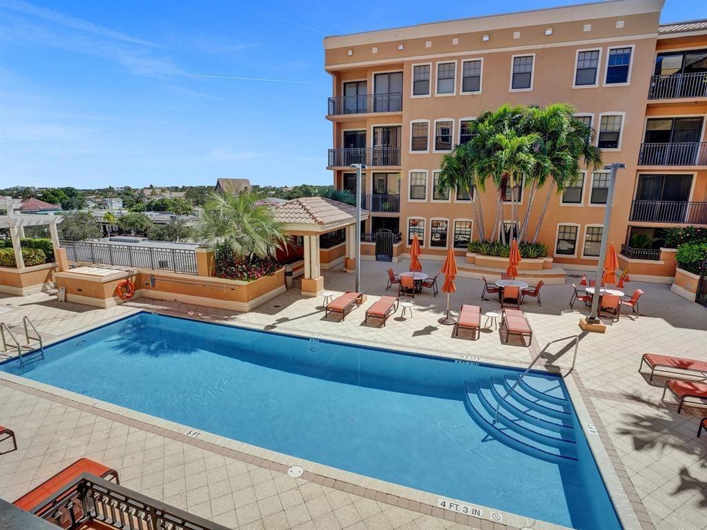 An outdoor swimming pool with lounge chairs and tables sits beside a multi-story building — 511 Lucerne Avenue # 616, FL 33460, FL