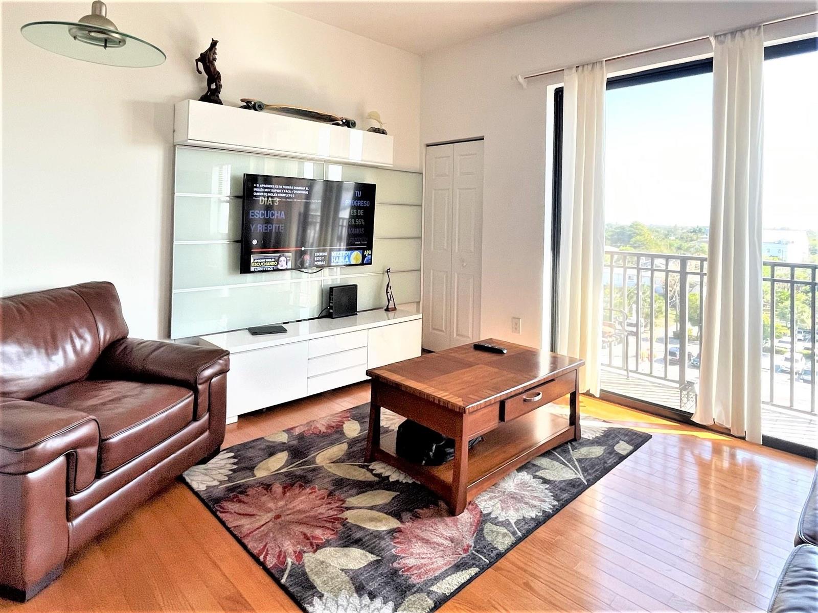 A living room features a brown leather sofa, a wooden coffee table, and a balcony view — 511 Lucerne Avenue # 616, FL 33460, FL