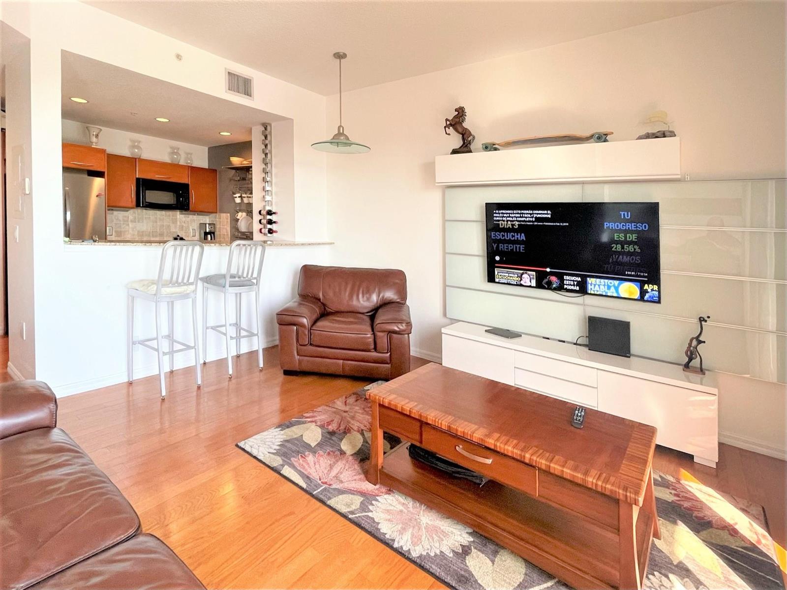 A living room features a leather armchair, a wooden coffee table, and a wall-mounted television — 511 Lucerne Avenue # 616, FL 33460, FL