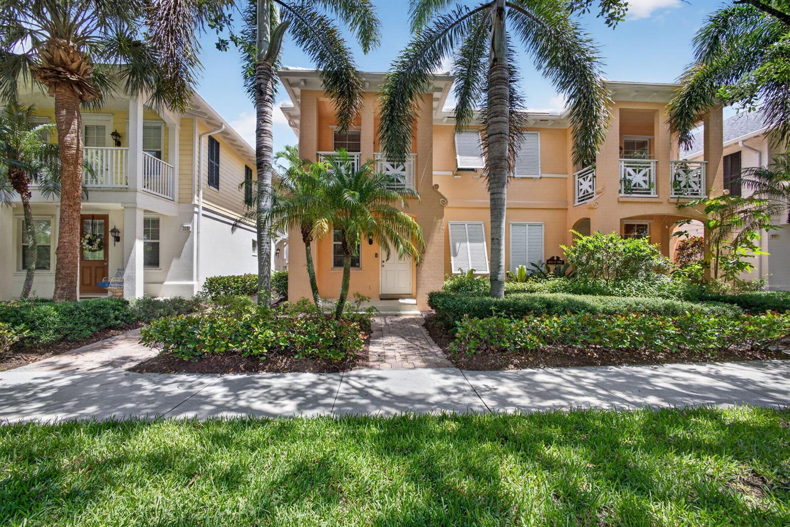 A two-story peach-colored house with palm trees and a sidewalk in the foreground — 219 Soriano Drive, Jupiter FL 33458, JUPITER, FL