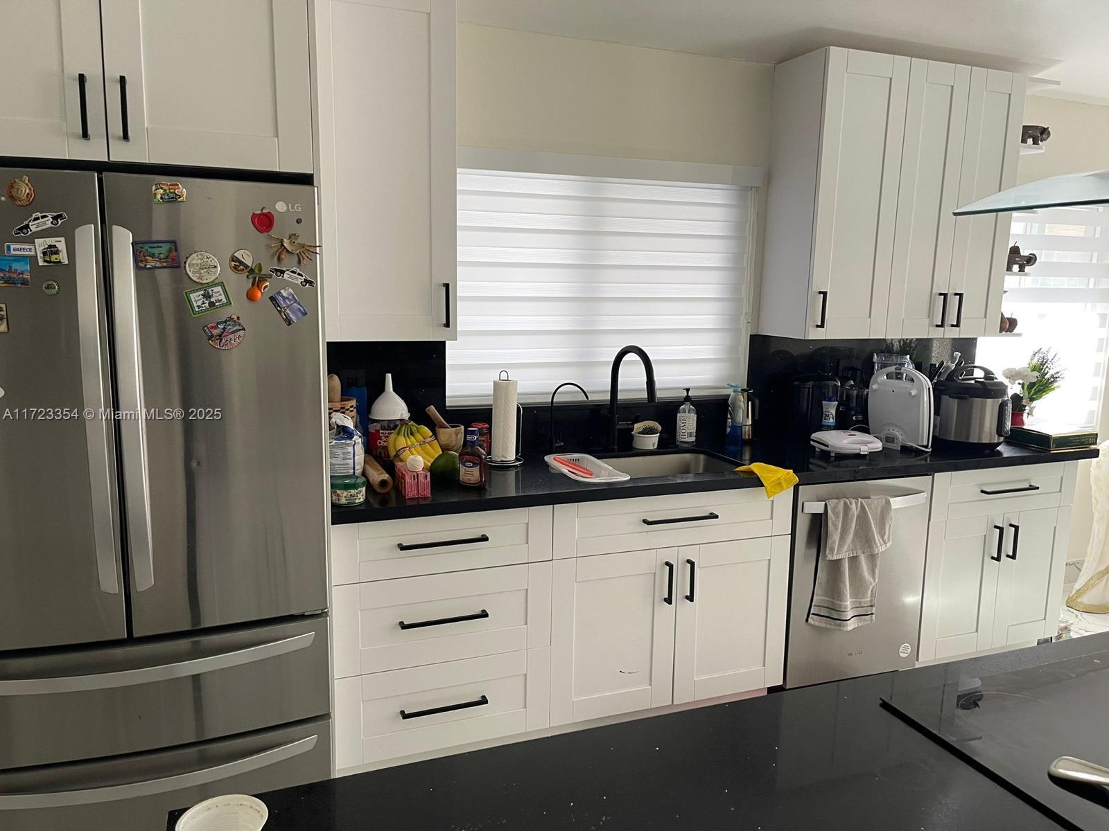 A kitchen features white cabinetry, black countertops, stainless steel appliances, and a window above the sink — 981 NW 134th Ave, Miami FL 33182, MIAMI, FL