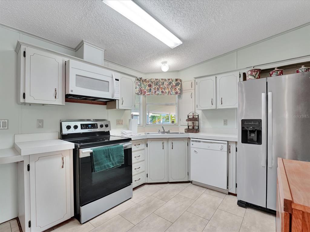 A kitchen with white cabinets, stainless steel appliances, and light-colored tile flooring — 118 SAINT PIERRES WAY, APOLLO BEACH, FL