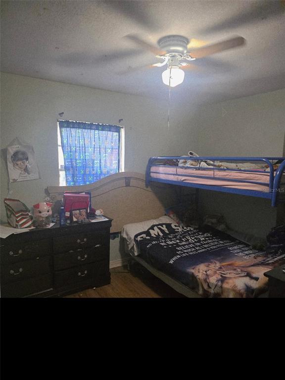 A bedroom features a blue metal bunk bed, a dark wood dresser, and a ceiling fan — 8311 N 18TH STREET, TAMPA, FL