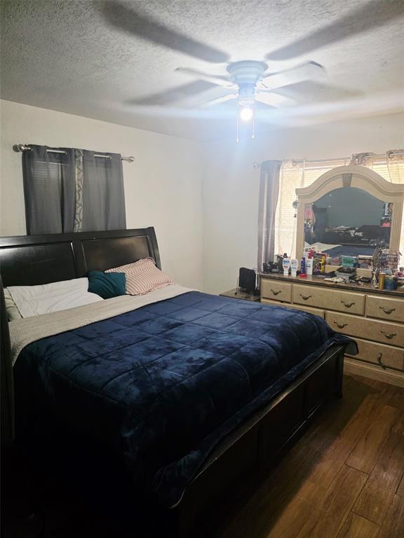 A bedroom features a dark wood bed frame, a matching dresser with a mirror, and wood-look flooring — 8311 N 18TH STREET, TAMPA, FL