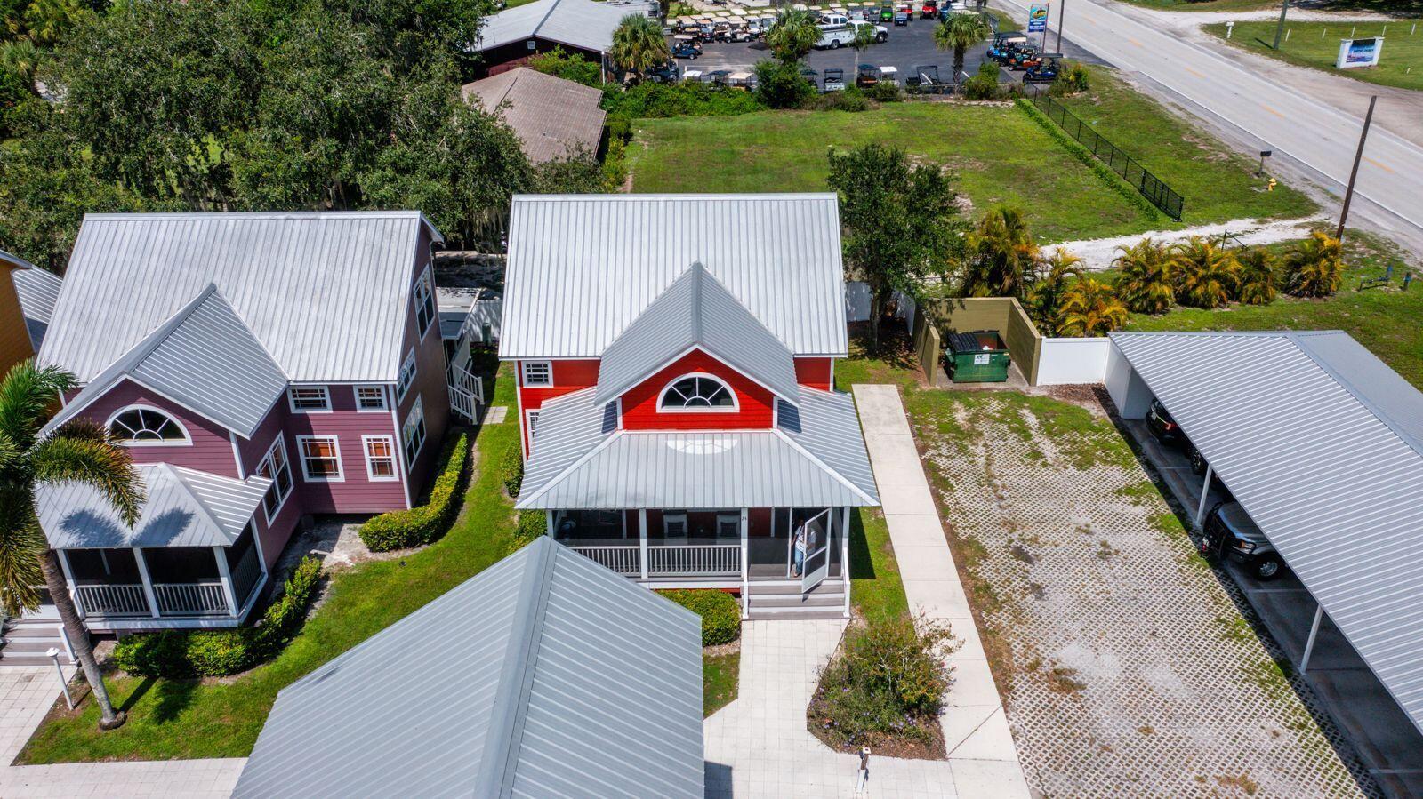 An aerial view shows a red house with a metal roof and a covered carport — 4334 Us-441, Okeechobee FL 34974, OKEECHOBEE, FL
