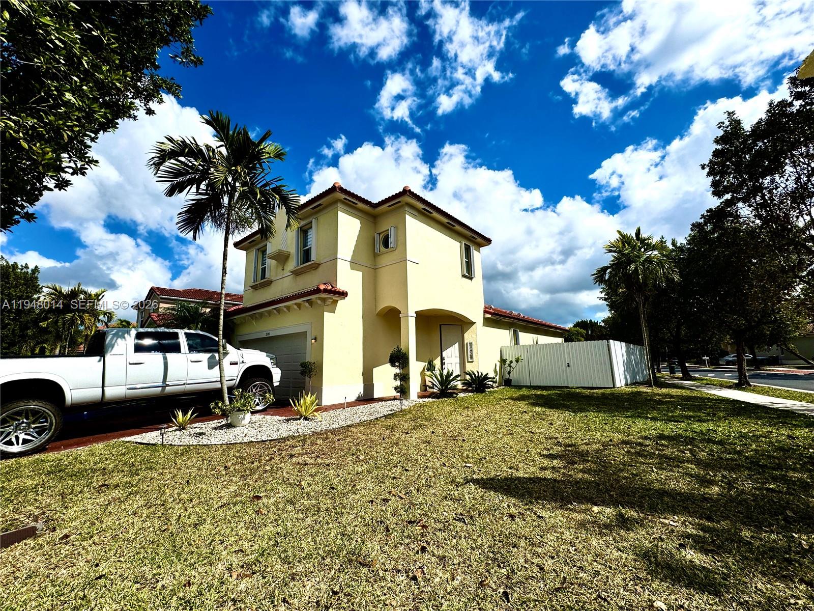 A two-story yellow stucco house with a white truck parked in the driveway — 2101 NE 37th Ter, Homestead FL 33033, HOMESTEAD, FL
