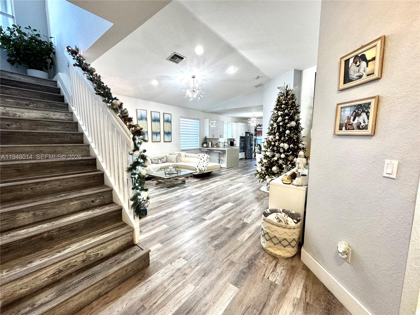 A staircase with wood-look flooring leads to an open-concept living area with a Christmas tree — 2101 NE 37th Ter, Homestead FL 33033, HOMESTEAD, FL