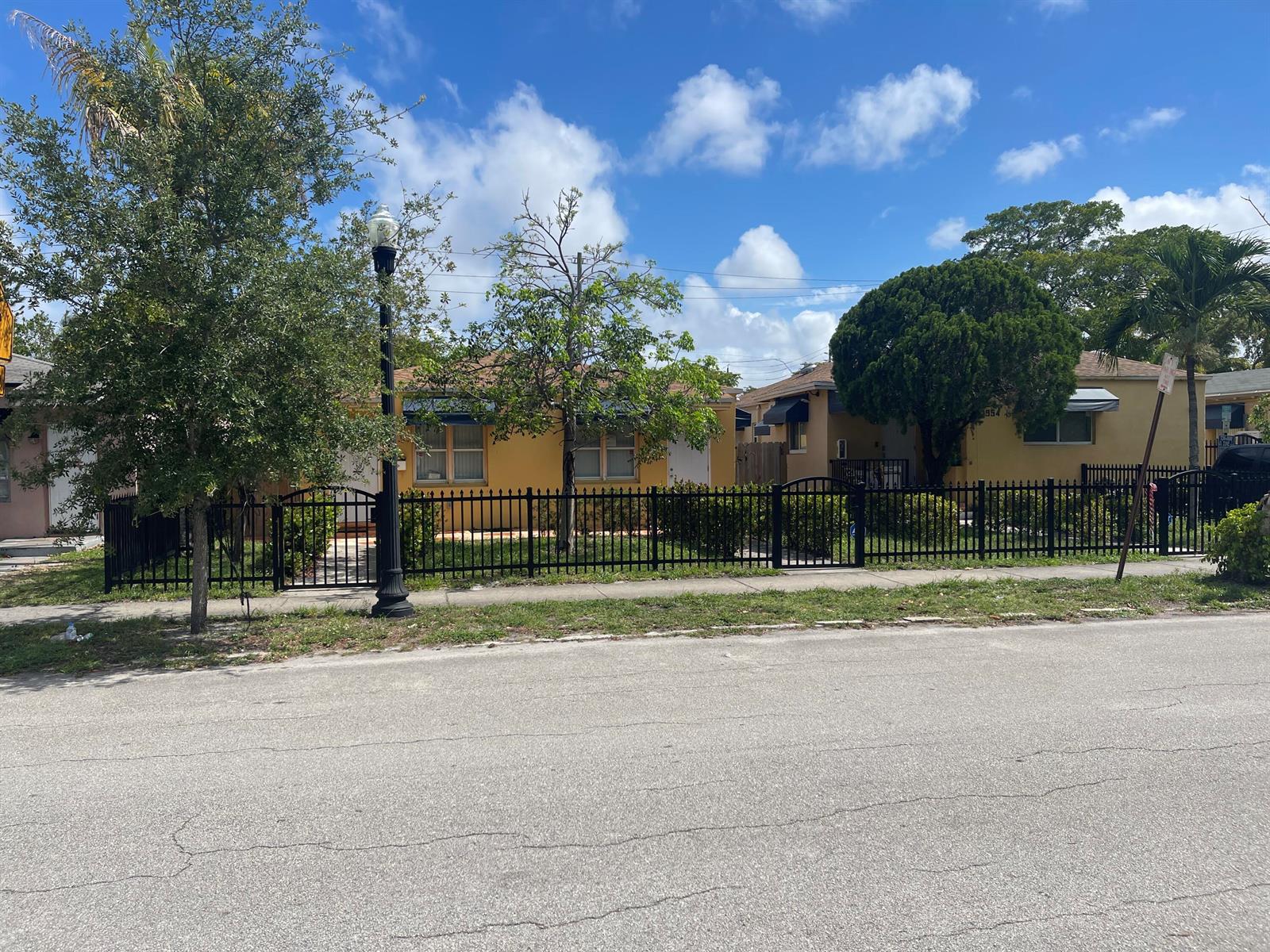 Two yellow single-story houses sit behind a black metal fence along a paved street — 615 N 20th Avenue, Hollywood FL 33020, HOLLYWOOD, FL