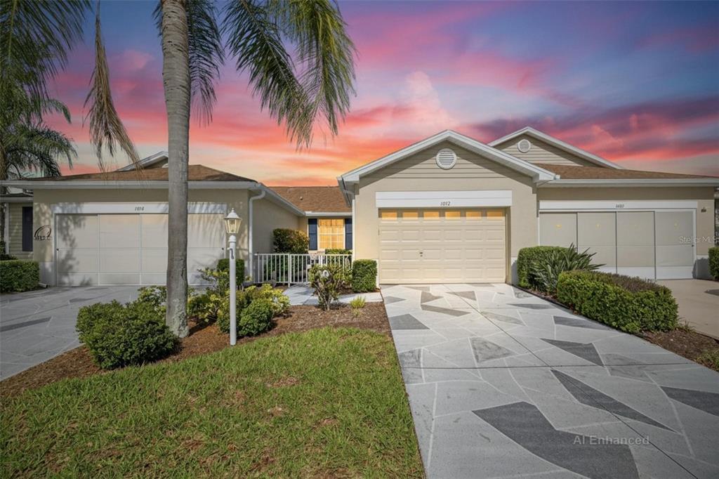 A tan single-story house with a patterned driveway and a palm tree at sunset — 1012 RADISON AVENUE UNIT 12, SUN CITY CENTER, FL