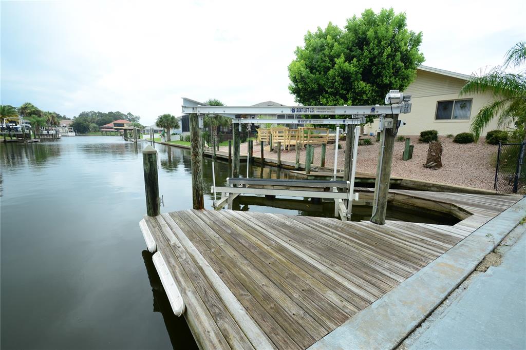 A wooden boat dock with a mechanical boat lift extends into a canal — 58 COMANCHE COURT, PALM COAST, FL