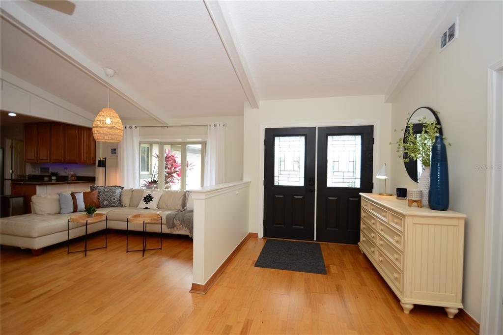 A living room with hardwood floors, a white sectional sofa, and black double entry doors — 58 COMANCHE COURT, PALM COAST, FL