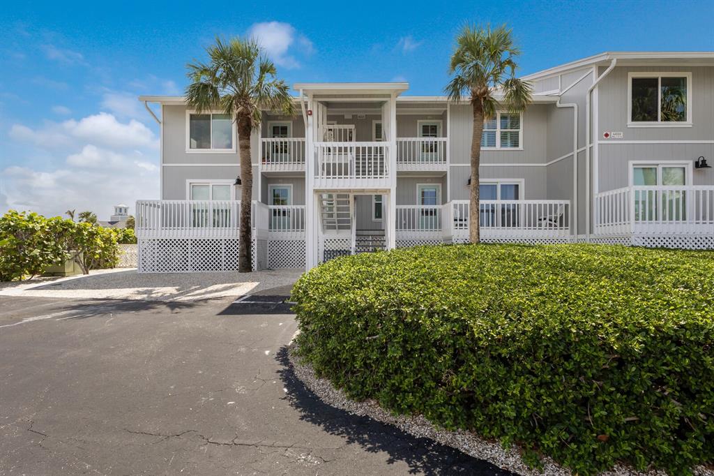 A two-story apartment building with white railings, palm trees, and a large green hedge — 6010 BOCA GRANDE CAUSEWAY UNIT C32, BOCA GRANDE, FL