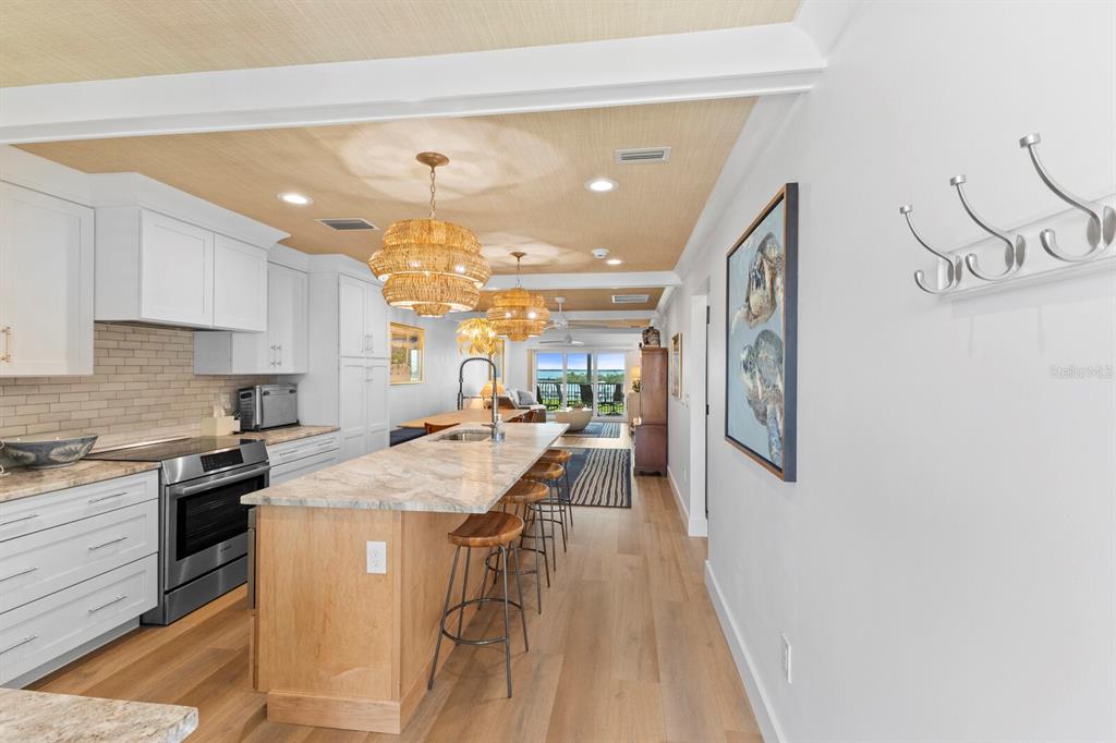 A kitchen with a wooden island, light wood floors, and woven pendant lights — 6010 BOCA GRANDE CAUSEWAY UNIT C32, BOCA GRANDE, FL