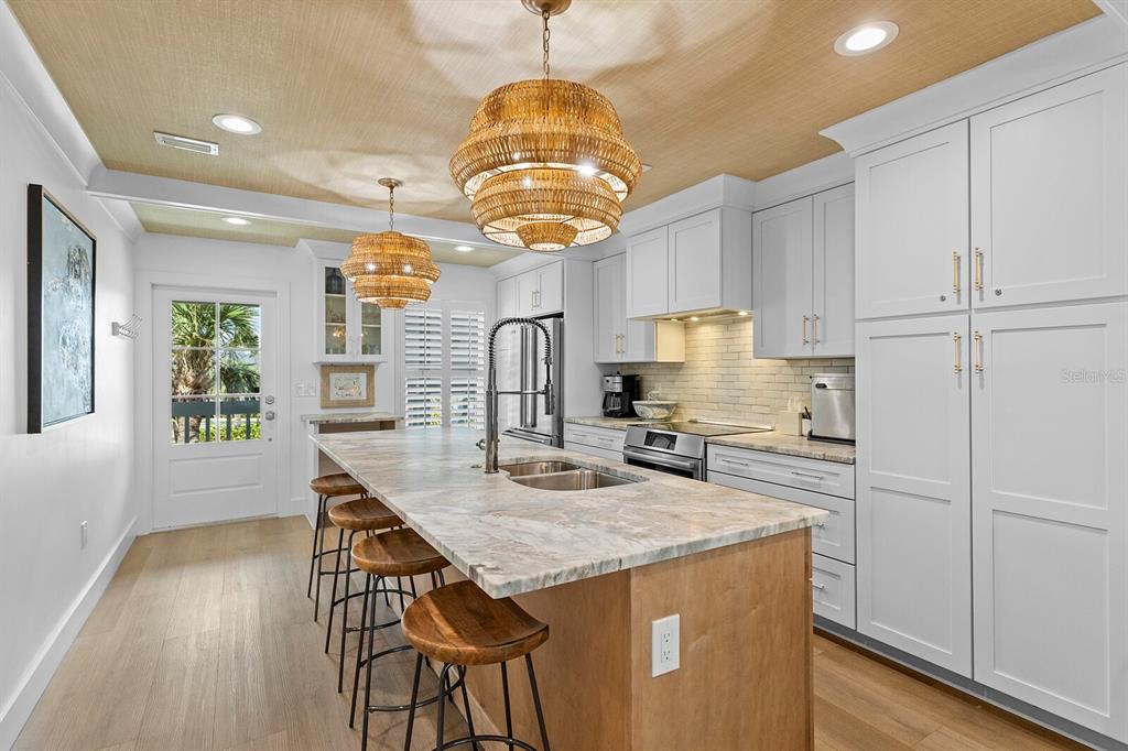 A kitchen features a large island with a stone countertop, white cabinetry, and woven pendant lights — 6010 BOCA GRANDE CAUSEWAY UNIT C32, BOCA GRANDE, FL