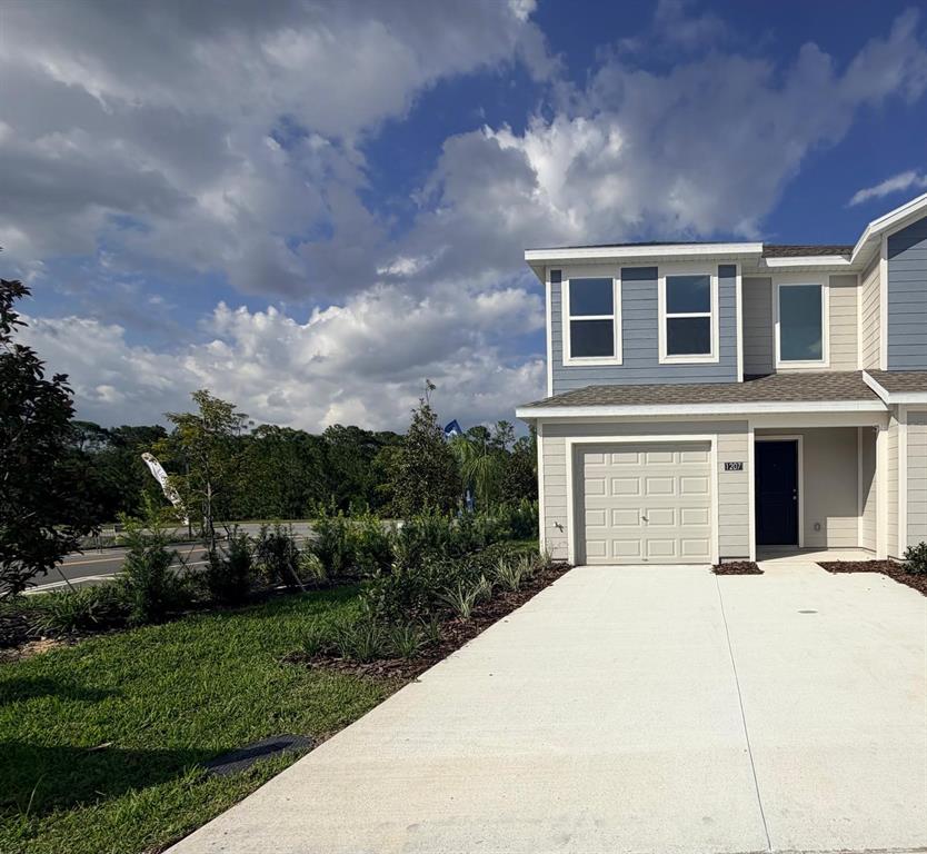 A two-story townhouse exterior features a beige garage, blue siding, and a concrete driveway — 1207 ORION STREET, DAVENPORT, FL