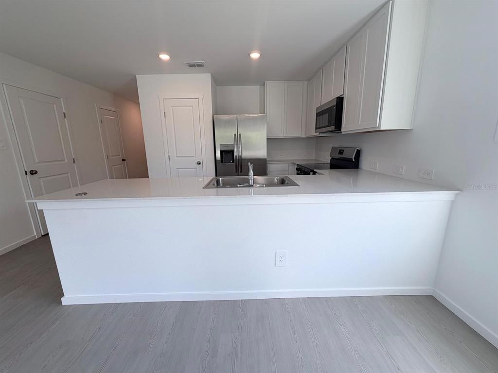A kitchen features white cabinets, stainless steel appliances, and a large island with a sink — 1207 ORION STREET, DAVENPORT, FL