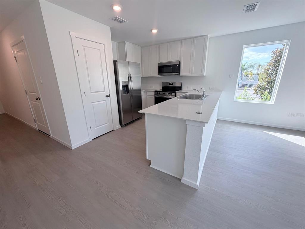 A modern kitchen features white cabinets, stainless steel appliances, and a quartz-topped island — 1207 ORION STREET, DAVENPORT, FL