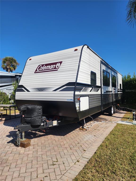 A white and black Coleman travel trailer is parked on a paved lot — 2418 LIMEWOOD AVENUE UNIT 302, CLERMONT, FL