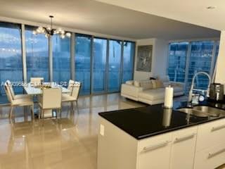 A modern open-concept living and dining area with floor-to-ceiling windows and a kitchen island — 465 Brickell Ave # 5402, Miami FL 33131, MIAMI, FL