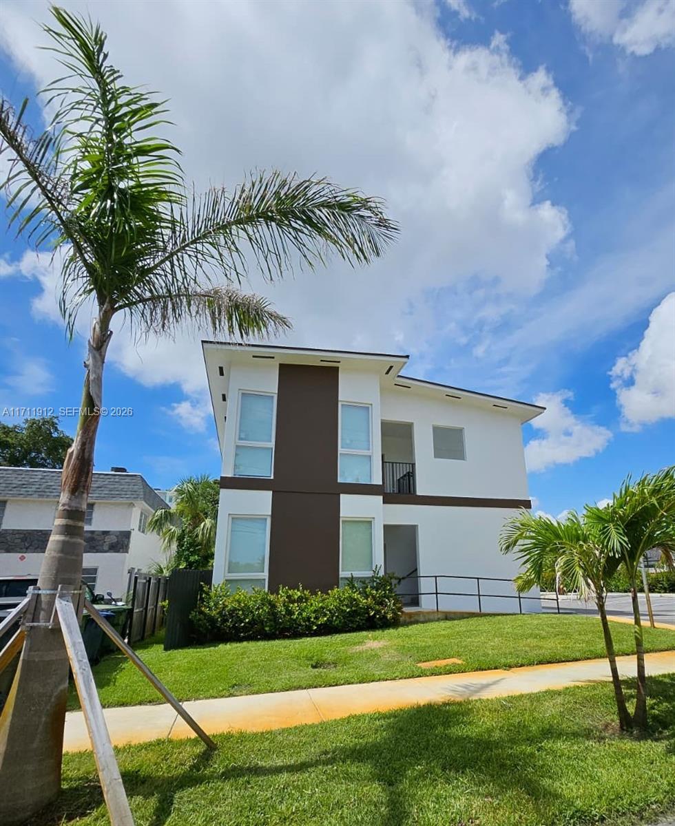 A two-story modern house with white and brown exterior walls stands beside a palm tree — 210 SE 10th St, Hallandale Beach FL 33009, HALLANDALE BEACH, FL
