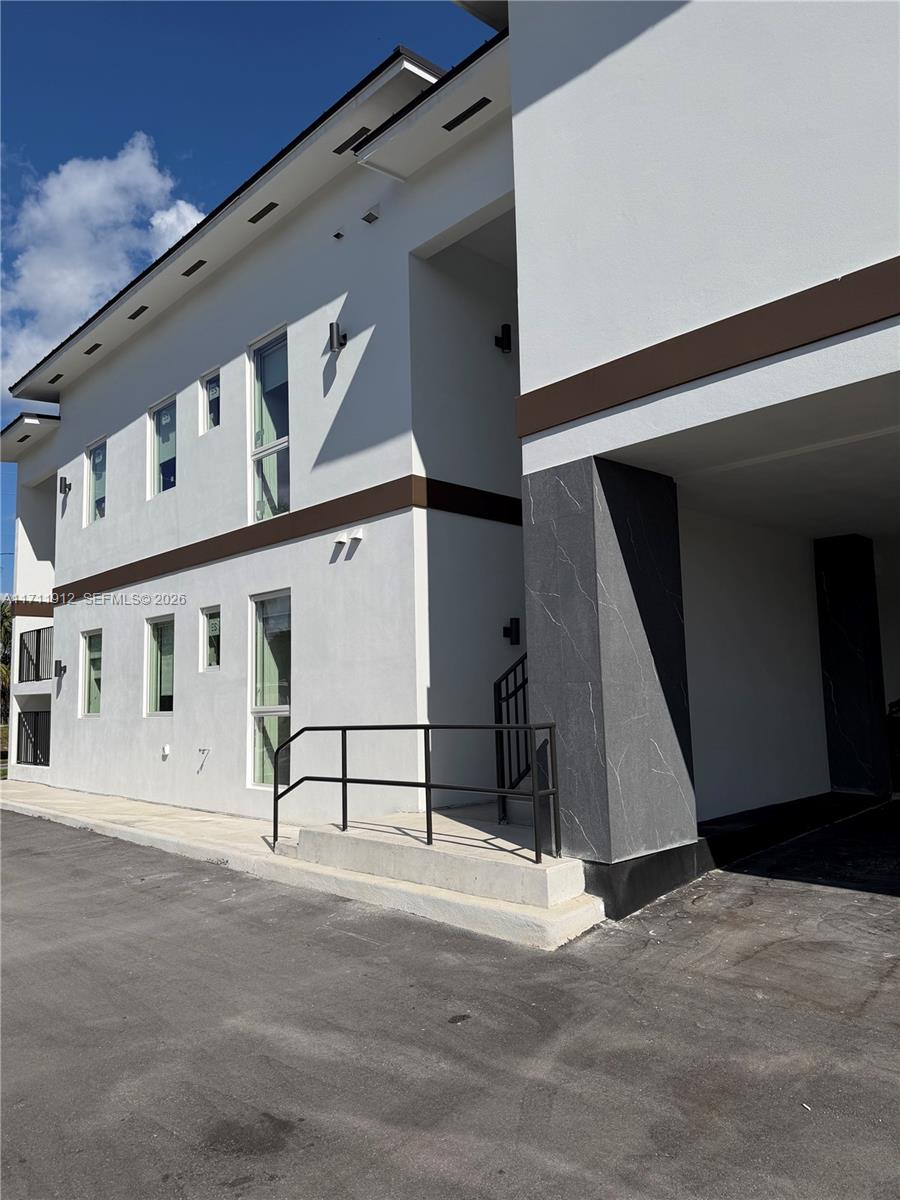 A modern two-story building exterior features white stucco walls, dark trim, and a concrete staircase — 210 SE 10th St, Hallandale Beach FL 33009, HALLANDALE BEACH, FL