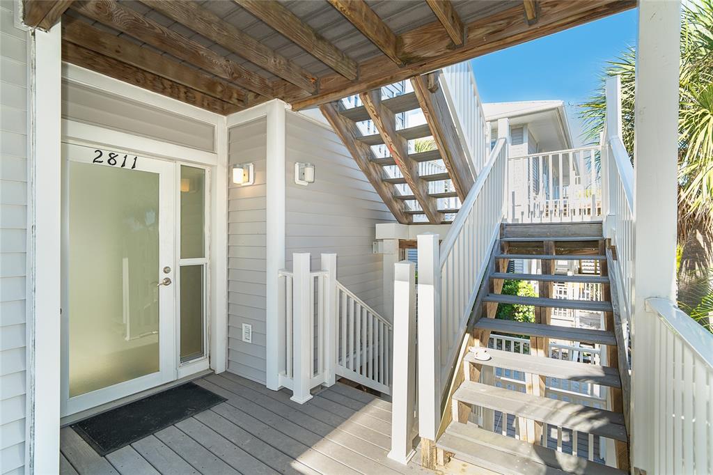 An exterior view of a building entrance with a frosted glass door and wooden stairs — 7470 PALM ISLAND DRIVE UNIT 2811, PLACIDA, FL