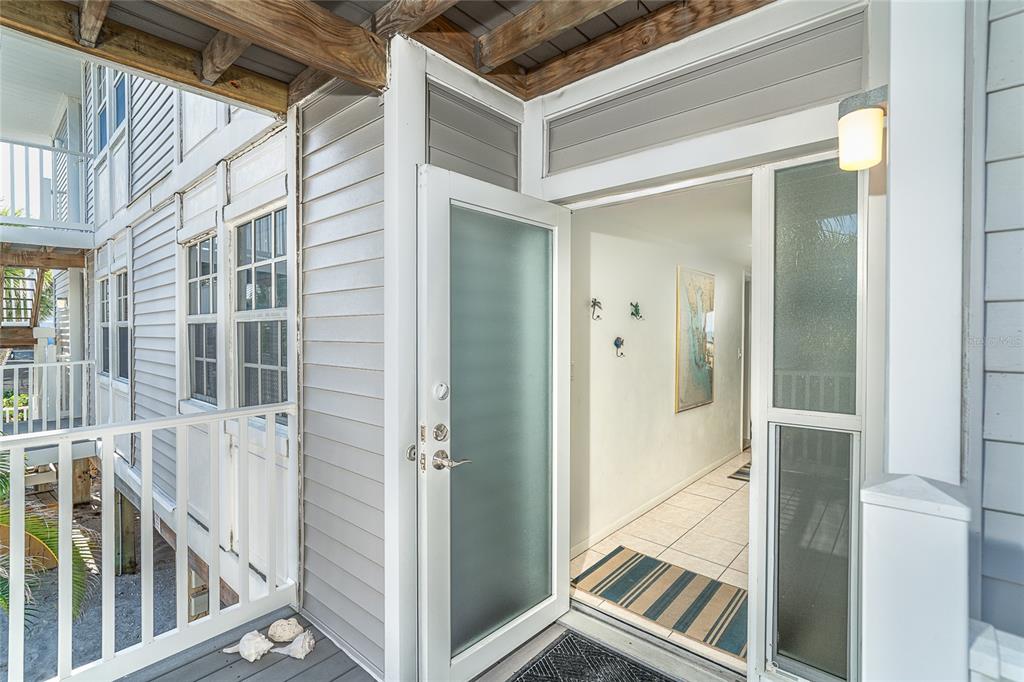 An exterior view of a building entrance with a frosted glass door and tiled hallway — 7470 PALM ISLAND DRIVE UNIT 2811, PLACIDA, FL