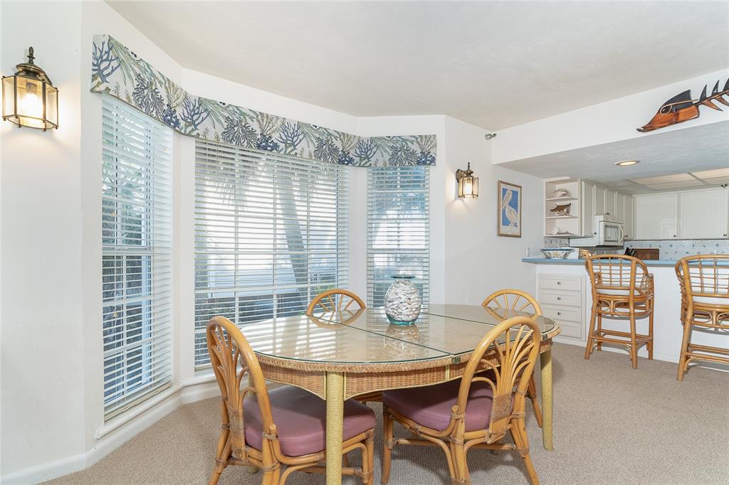 A dining area features a glass-topped rattan table, matching chairs, and a bay window — 7470 PALM ISLAND DRIVE UNIT 2811, PLACIDA, FL