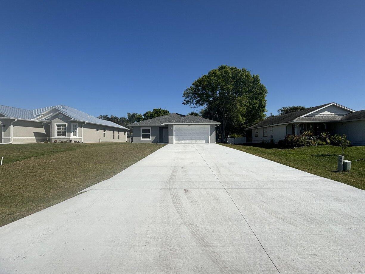 A gray single-story house with a white garage door and a long concrete driveway — 1330 28th Avenue, Vero Beach FL 32960, VERO BEACH, FL